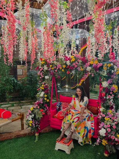 A wide shot of the bride on a beautifully decorated swing, showing her full bridal henna on both hands and feet.