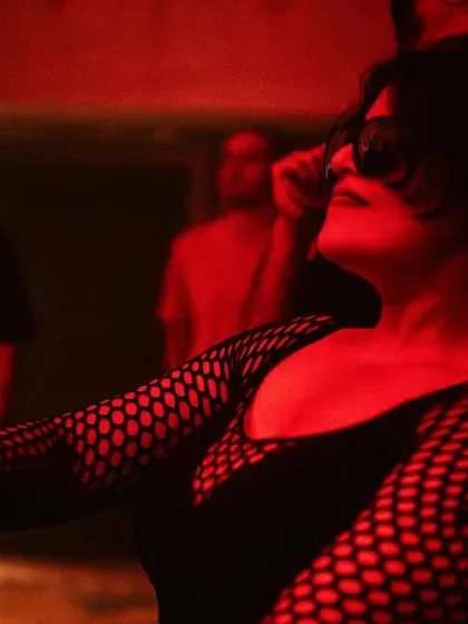 A guest in a mesh top dances, caught in the red glow of the party. Our events attract a stylish crowd that is passionate about music and nightlife.