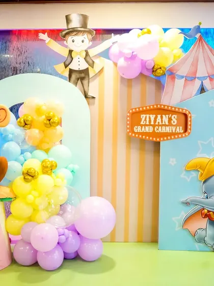 A sweet photo corner at a pastel carnival party, featuring Dumbo and a circus monkey prop.