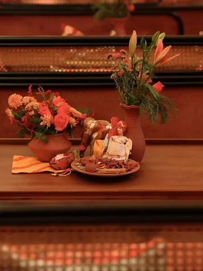 A tabletop detail featuring small Rajasthani dolls, clay pots with flowers, and a tray of spices, creating a scene full of character and local charm.