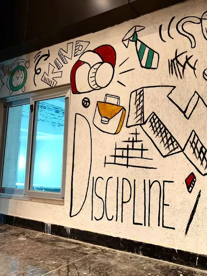 Another part of the hostel wall, with words like "Discipline" and "Kindness" doodled alongside relevant icons.