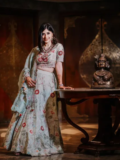 A full-length portrait of the bride in her pastel lehenga, posing in an elegantly decorated room. This shot showcases her complete look and the sophisticated venue.