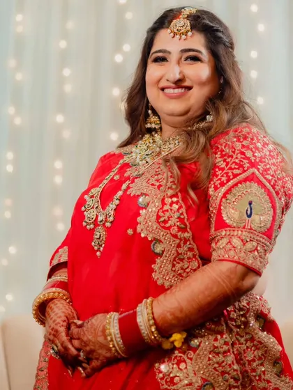 A full view of her stunning red reception outfit. The makeup and hair were designed to complement the intricate embroidery and heavy jewelry.