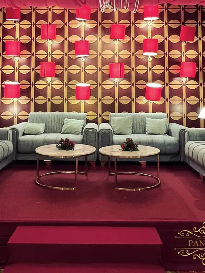 The main seating lounge, featuring a unique backdrop wall with a geometric print and red lampshades, creating a retro-glam vibe.