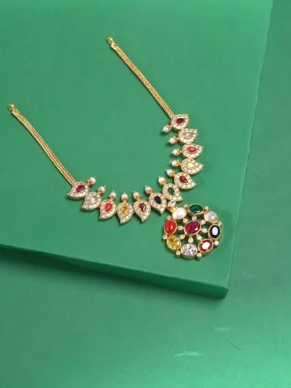 A vibrant Navratna-style necklace, featuring nine different colored stones in a beautiful arrangement. The centerpiece is a circular cluster of gems, with leaf-shaped stones forming the chain.