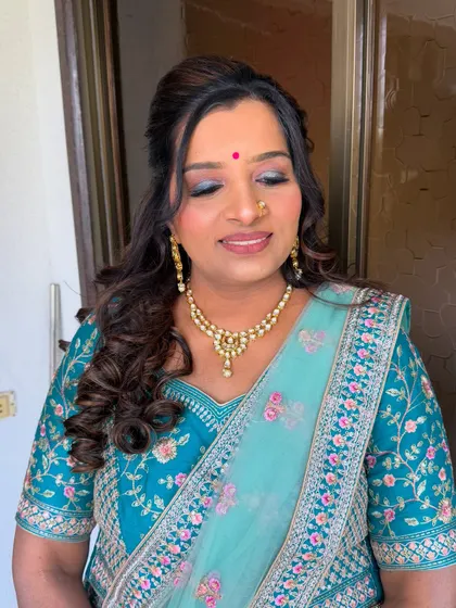 A beautiful soft glam look on a client in a teal saree. The makeup features a shimmery blue-green eyeshadow and a warm lip color.