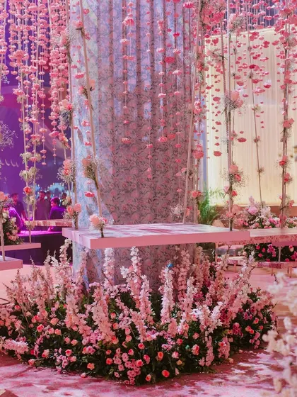 I designed this whimsical space to feel like a daydream. Hanging floral swings are suspended amidst a shower of pink blossoms, creating an interactive and utterly romantic setting that invites guests to become part of the decor.