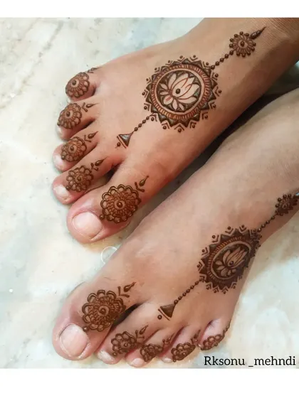 Simple and elegant feet mehndi. This design features a central lotus mandala on the top of the foot, with matching delicate patterns on the toes, like beautiful, permanent jewelry.