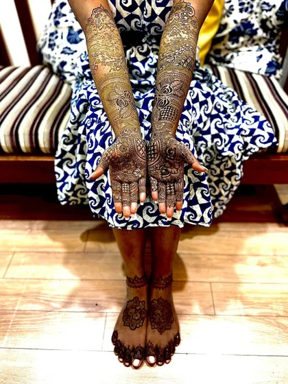 A complete bridal look with detailed henna on both arms and feet. The designs are traditional and dense, providing the full coverage many brides dream of for their wedding photos.