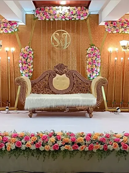 This engagement stage features a rich, textured gold backdrop with beautiful pink and peach floral arrangements. The design is both classic and modern, suitable for a variety of celebratory events.