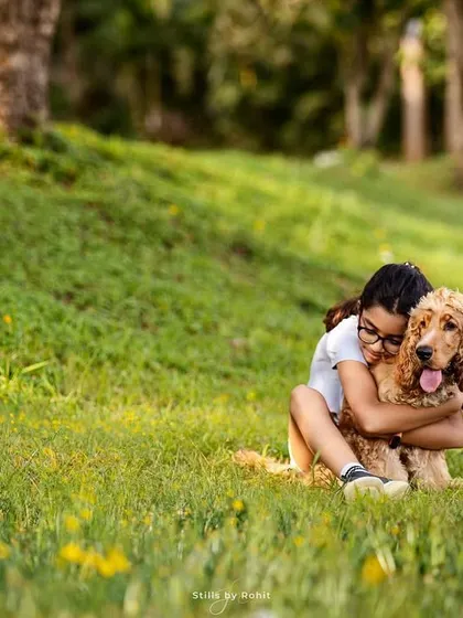 A girl shares a heartfelt hug with her Cocker Spaniel in a lush green park. The bond between children and their pets is so pure, and it's an honor to freeze these moments of friendship in time.