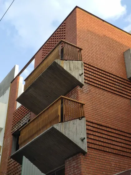 A dynamic composition of stacked balconies made of exposed brick and concrete, showcasing a robust and modern urban aesthetic.