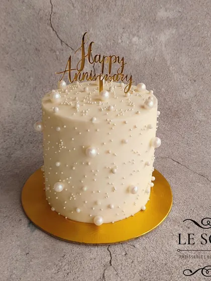 This cake is proof that simple can be stunning. A Strawberry Cream Cheese cake covered in white buttercream and adorned with different sizes of edible pearls for an anniversary.