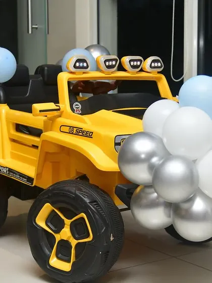 Another option for a baby's entry, this yellow toy jeep is decorated with blue, white, and silver balloons to match the party's color scheme.