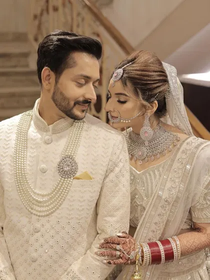 A classic couple portrait. The bride and groom look perfectly coordinated in their white outfits, and her makeup is timeless and elegant.