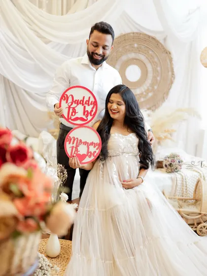 A joyful announcement photo with "Mommy to be" and "Daddy to be" signs. Their happy expressions are contagious.