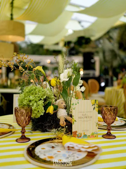 A close-up of the beautiful tablescape. We used yellow and white striped linens, vintage-style colored glassware, and lush floral centerpieces to create a cheerful and elegant dining experience for the baby shower guests.