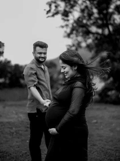 A beautiful black and white candid moment. The wind catches her hair as she smiles, holding his hand. It feels natural and full of life.
