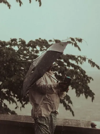 A person struggles with their umbrella in the wind, a familiar sight during the Mumbai monsoon.