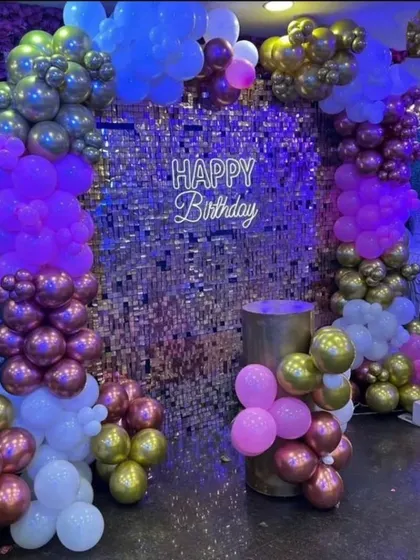 Another view of a glamorous first birthday setup, showing the interplay of the sequin wall, colorful metallic balloons, and the marquee number '1' under party lights.