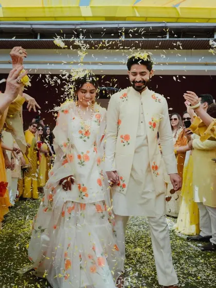 A full-length shot of the couple at their Haldi, showcasing their beautifully coordinated floral outfits.
