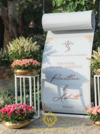 A beautiful welcome sign designed as a scroll, surrounded by elegant pink floral arrangements. This detail set a romantic and traditional tone for the wedding ceremony.
