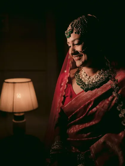 The bride's face is illuminated by a soft lamp light, her smile creating a warm and intimate portrait.