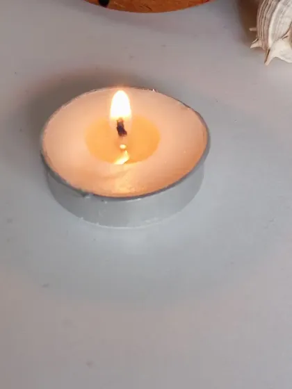 A single, lit tealight on a clean white surface. Sometimes the simplest things are the most beautiful, creating a peaceful retreat with just a small flame.
