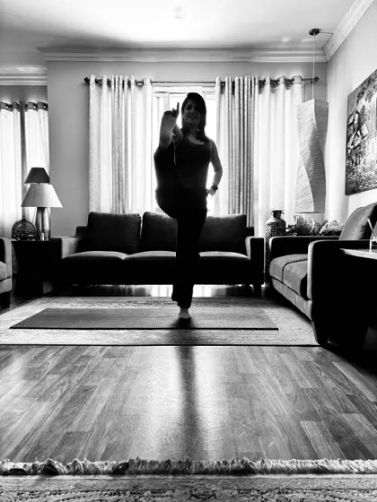 Standing on one leg with the other knee drawn up, a balance practised at home.