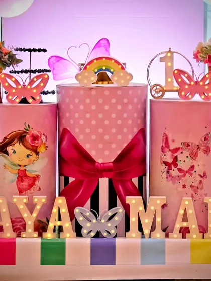 A close-up of the themed pedestals and marquee letters for the twins' butterfly party. The light-up rainbow and number '1' add to the festive display.