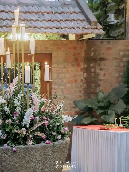 A large stone urli filled with flowers and a candelabra, a stunning decor piece for an evening event.