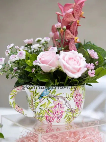 A beautiful floral arrangement in a teacup, a detail from a Paris-themed baby shower. This small touch adds to the chic and delicate "parisian tea party" vibe.
