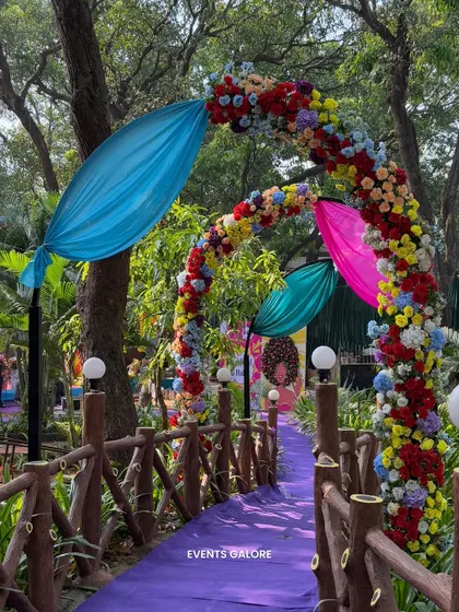 A beautiful floral archway in bright, multi-colored flowers guided guests over a small bridge into the main carnival area, with a purple carpet adding another pop of color.