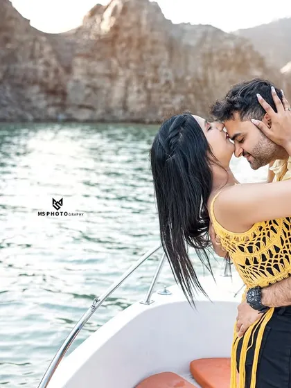A close-up, passionate kiss on a boat. This image focuses purely on the couple's connection, with the beautiful lake and mountains creating a perfect natural background.