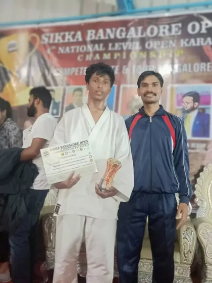 A student holding his certificate and trophy after a win at the 4th Sikka Open National Level Karate Championship 2022.