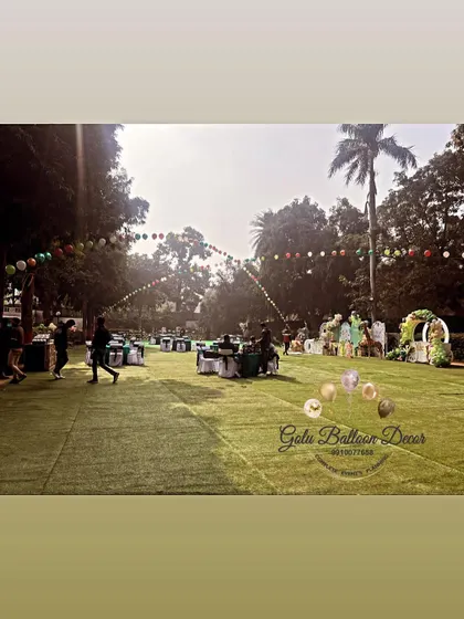 A wide shot of an outdoor party setup on an artificial grass lawn, getting ready for a jungle-themed celebration.