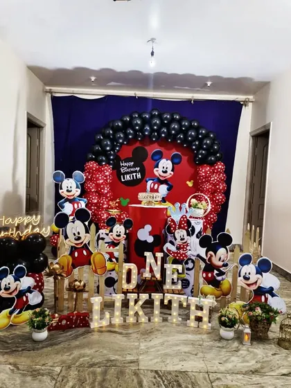 Oh boy! A classic Mickey Mouse theme for Likith's first birthday. This setup features a red and black balloon arch, numerous Mickey Mouse cutouts in different poses, and a light-up name sign for a timeless party.