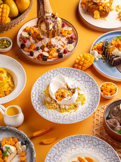 A vibrant mango festival spread at Bastian. The bright yellow and orange tones create a cheerful and appetizing image that celebrates the seasonal menu.