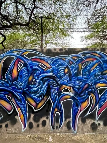 A complex, bio-mechanical style piece in blue and orange. The letters look like they are made of alien or insect-like parts.