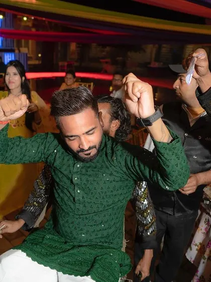The groom letting loose on the dance floor during a pre-wedding celebration like Mehendi or Sangeet, surrounded by friends and family.