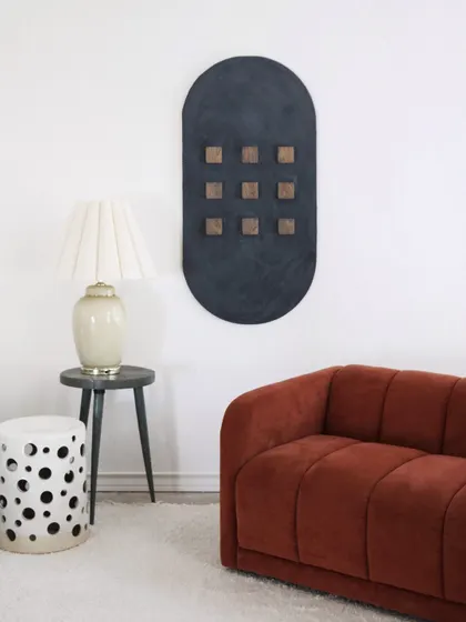 This minimalist modern wall art features a unique oval shape with raised wooden squares on a textured black background, offering a subtle yet intriguing design.