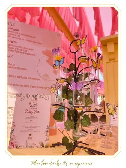 A whimsical Bubbly Bar setup featuring a butterfly-adorned glass tree. This creative display is perfect for garden parties, brunches, or whimsical wedding themes.