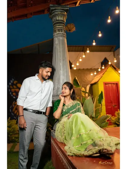 A charming pre-wedding photo at dusk. The warm string lights and rustic setting create a cozy and intimate atmosphere.