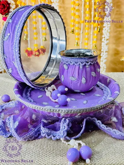 For those who love a bit of glam, this purple Karvachauth thali set is perfect. The fabric has a subtle shimmer, and the entire set is coordinated with matching beaded hangings for a complete, luxurious look.