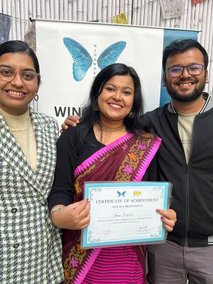 A winner poses with her certificate, supported by friends and family. Our community is a supportive one.