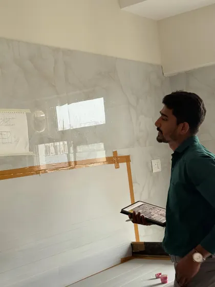 On-site, comparing the digital plan on my tablet to the actual wall where a marble-finish panel is being installed.