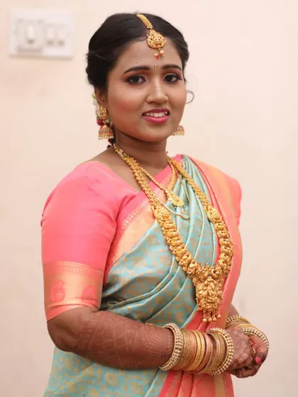 Another angle of this beautiful Muhurtham look, showing how the makeup enhances her smile. The gold jewelry and pastel Kanjivaram saree are perfectly coordinated for a timeless appearance.