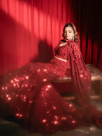 The ruby red lehenga catches the light, showcasing the sparkle of its full embellishment. A look designed for grace and glamour.