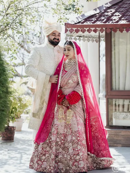 A full-length portrait of the couple in a beautiful garden setting, capturing the grandeur of their wedding attire.