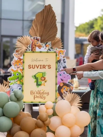 A candid moment as the family arrives at Suvir's jungle-themed first birthday party. The personalized welcome sign with cute safari animals is the perfect start to the celebration.